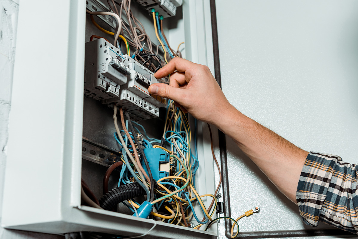 cropped view of electrician touching switch on switchboard