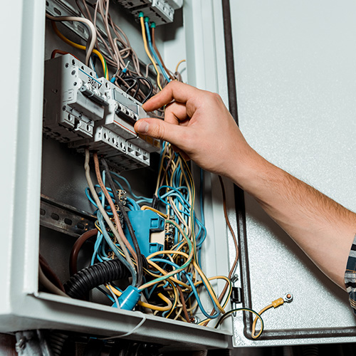cropped view of electrician touching switch on switchboard