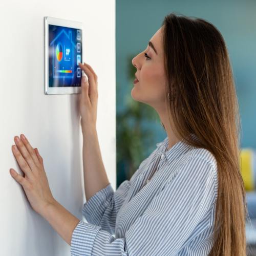 Pretty young woman using the home automation system on digital tablet to regulate the temperature.