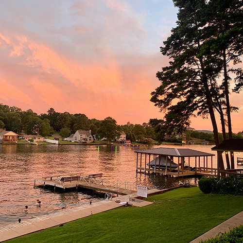 Sunset at the lake, boats docks and trees. Kids swimming