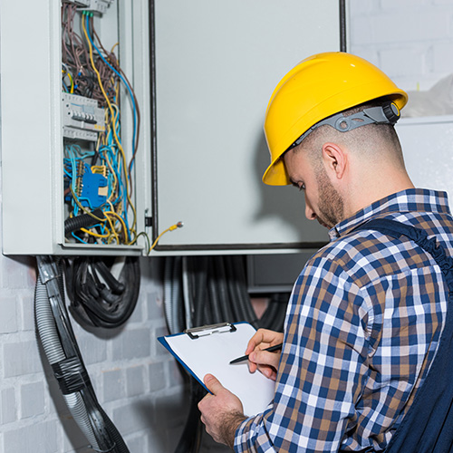 Professional electrician inspecting wires in electrical box