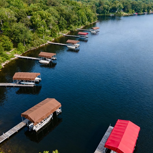 Covered boat docks along a calm wooded lakeshore
